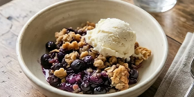 Blueberry crisp topped with vanilla ice cream and buttery crumble topping