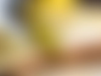 Lemon cake with white icing, topped with lemon slices and flowers, sits on a wooden board with lemons and a mug in the background.