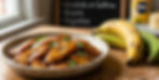 Bowl of caramelized plantains garnished with cilantro on a wooden table beside ripe bananas. Chalkboard lists dishes: Ensalada de Gallina, Arepas, Tequeños.