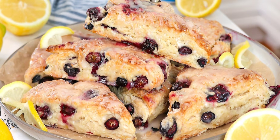 Blueberry lemon scones stacked together with visible fresh blueberries and lemon garnish
