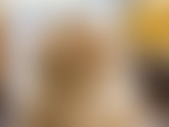 Smoothie in a jar topped with banana slices, oats, and chia seeds. Spoon inside. Background has bananas and a glass on a table.