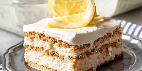 a slice of Lemon Icebox Cake with a twisted slice of lemon  served on a gray plate.