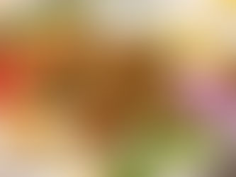 Bowl of falafel, hummus, rice, cucumber, tomatoes, red onion, tzatziki, and lemon slices, garnished with parsley on a neutral tablecloth.