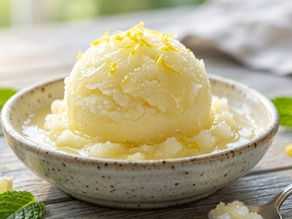 Lemon sorbet in a speckled bowl with mint and lemon wedges on a rustic table, bright and refreshing dessert scene