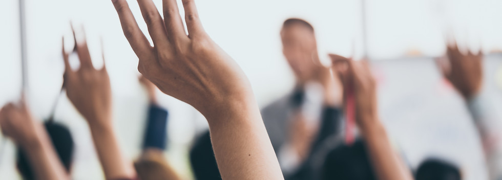 Audience raising hands up while businessman is speaking in training at the office..jpg