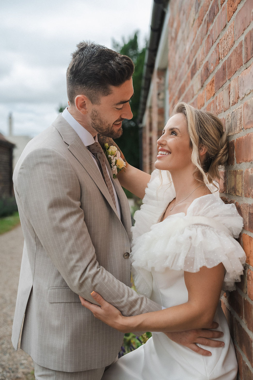 Couple embracing along a brick wall