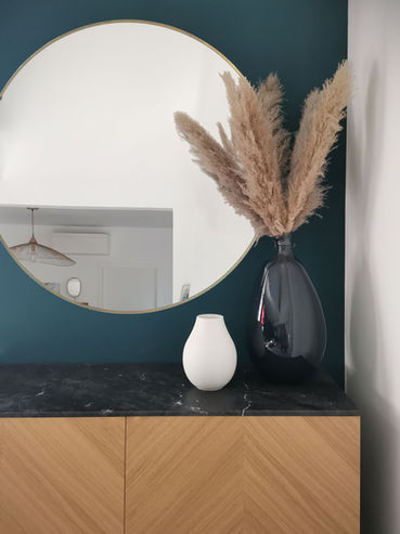 Maison Perrier, Décoration d'intérieur à Six-Fours-Les-Plages / Peinture bleue pétrole qui fait ressortir le meuble en finition bois et le miroir rond.