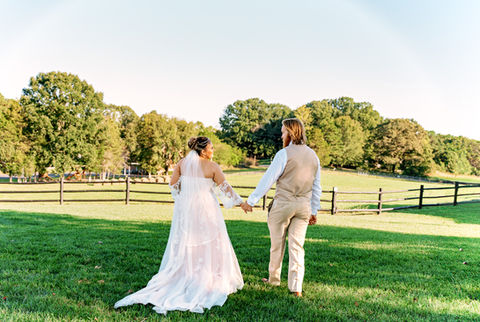 Wedding Couple holding hands in a field.