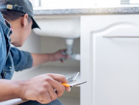 A professional checking a pipe under the sink