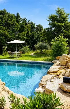 Elegant villa pool terrace featuring a heated pool and hot tub with views of apple orchards near L'Isle-sur-la-Sorgue.