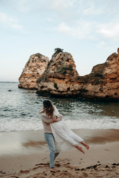 Couple running and spinning on Praia do Camilo beach.