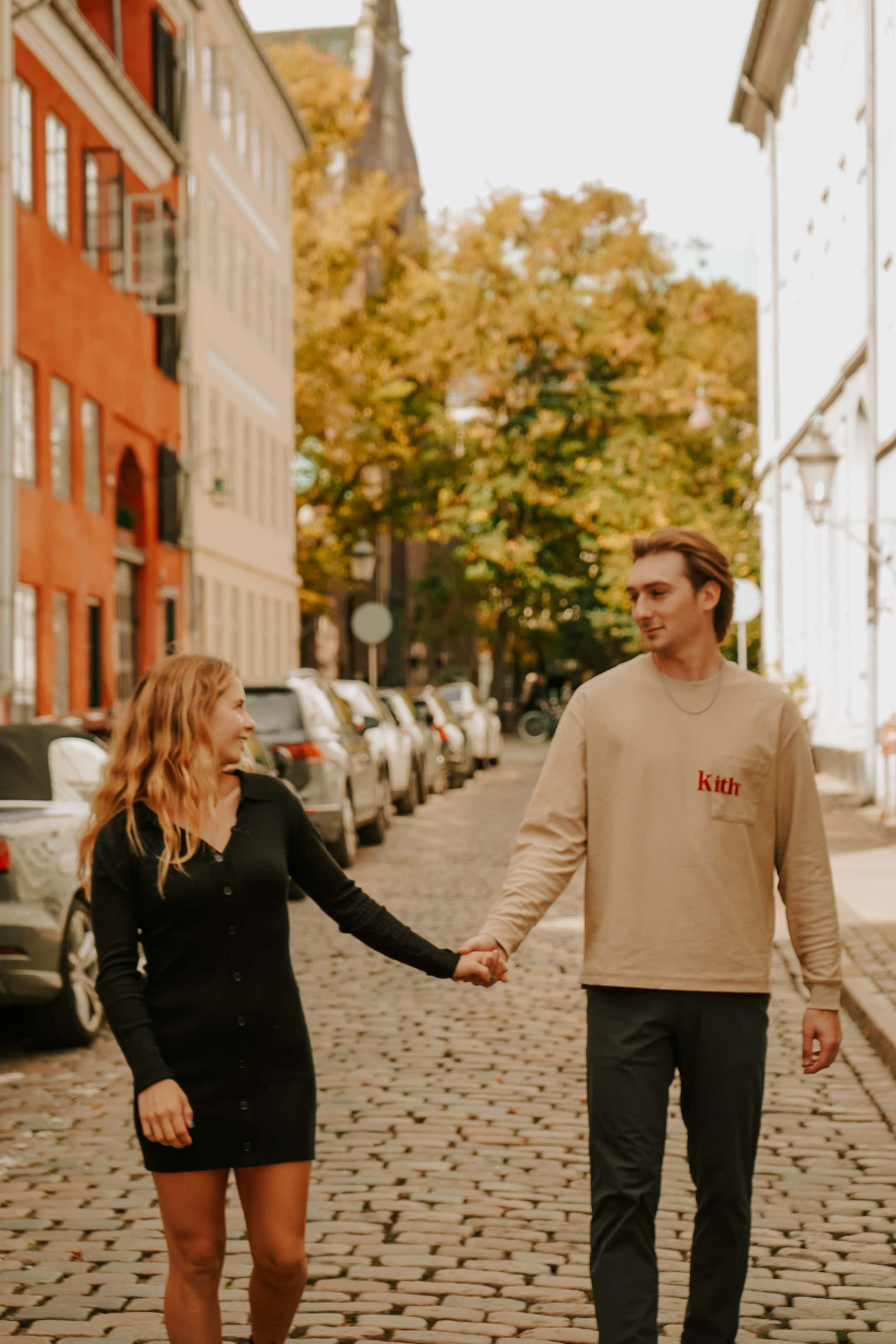 Smiling couple walking hand in hand through Copenhagen's cobblestone streets