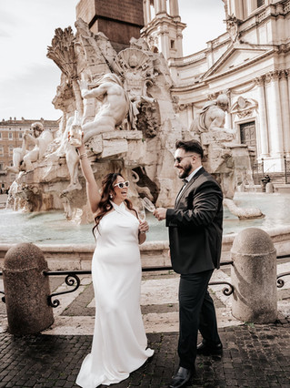 A wedding couple posing with champagne in front of the beautiful Piazza Navona
