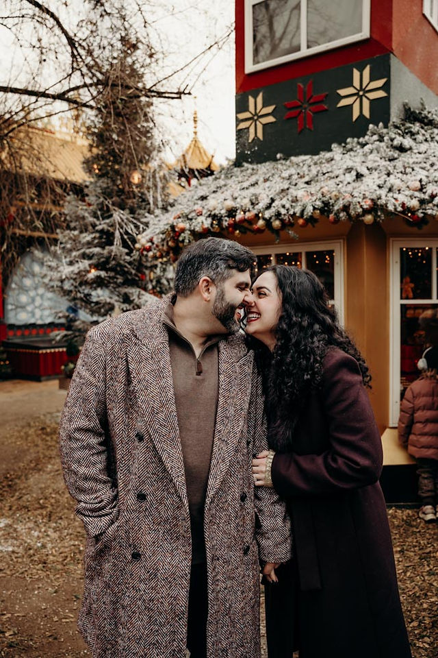 Romantic couple walking through Tivoli Gardens with Christmas decorations and snow