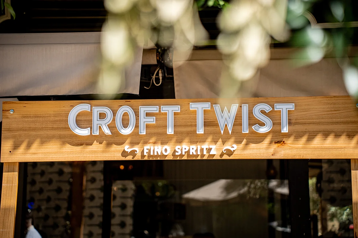 CROFT TWIST    El spritz ya no habla solo italiano, sino que ahora tiene acento andaluz. Croft Twist es una propuesta que cambia el prosecco por vino fino y convierte el aperitivo en algo más fresco, ligero y sorprendente. Con una graduación de apenas 5,5º, esta bebida se ha ganado un hueco entre quienes buscan alternativas más suaves sin renunciar al sabor ni al ritual de la copa al atardecer.      Su fórmula mezcla finos elegantes elaborados en las bodegas centenarias de González Byass con ingredientes naturales como hierbabuena y limón, dando lugar a un perfil cítrico, delicado y muy fácil de beber. La burbuja es fina, ligera y pensada para acompañar esos tardeos interminables que empiezan sin saber cuándo terminan. Croft Twist representa una nueva generación de aperitivos: menos intensos, más espontáneos y ligados a momentos sociales diurnos donde importa tanto la bebida como el ambiente que la rodea.   