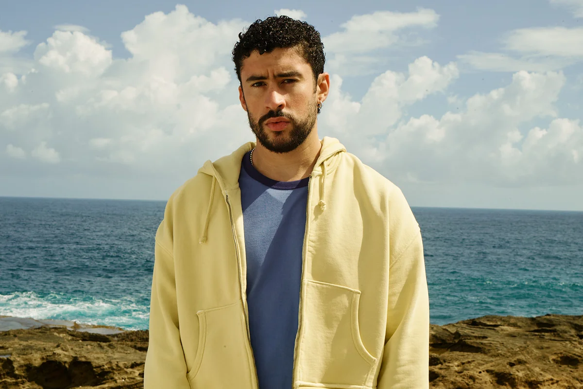 “Un verano en NUEVAYoL”… con Benito aterrizando en España. Coincidiendo con el arranque de sus conciertos en España, la marca de Inditex lanza BENITO ANTONIO, una cápsula de casi 150 piezas que traduce el universo estético del artista puertorriqueño a prendas pensadas para el día a día. Oversize, sastrería relajada, camisetas gráficas, bermudas amplias, bandanas y tejidos ligeros forman parte de una propuesta que bebe directamente de Puerto Rico y de esa manera despreocupada —pero muy medida— de vestir que define a Benito. Lejos de parecer el típico merchandising de gira, la colección funciona como una extensión real de su estilo personal: colores vibrantes, siluetas cómodas y ese punto entre urbano y nostálgico que domina también sus últimos trabajos musicales. Además, llega en uno de los momentos de mayor locura, con fans agotando prendas en cuestión de horas y preparando looks para los conciertos de Madrid y Barcelona.