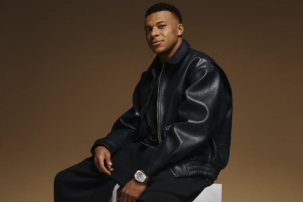 La alta relojería y el deporte de élite volvieron a encontrarse en Madrid de la mano de Hublot y Kylian Mbappé. La presentación del nuevo Big Bang Reloaded Kylian Mbappé mostraba en público una edición limitada que convierte la personalidad y ambición del futbolista en una auténtica pieza de colección limitada a solo 200 unidades. La pieza destaca por su poderosa estética contemporánea y por reflejar el ADN innovador de la manufactura suiza. Fabricado en cerámica blanca pulida y oro King Gold de 18 quilates, el modelo incorpora detalles profundamente ligados al jugador, entre ellos el grabado “Trust Yourself” en el bisel o el número 10 en tono dorado, guiño directo a su icónica camiseta y a la filosofía que ha marcado su trayectoria profesional. Más allá de su diseño, el Big Bang Reloaded Kylian Mbappé también representa la excelencia técnica de la firma. En su interior alberga el calibre UNICO, uno de los cronógrafos integrados más avanzados de la firma suiza, capaz de combinar innovación mecánica y precisión de alta relojería con una estética deportiva y sofisticada. La presentación tuvo lugar en un exclusivo evento celebrado en el centro de Madrid, reunión de figuras del deporte, la moda y el entretenimiento como la estrella de la selección francesa, Iker Casillas o Paula Echevarría, entre otros, disfrutando de música en directo, una cuidada puesta en escena y una atmósfera contemporánea que celebraba la llegada de todo un icono.