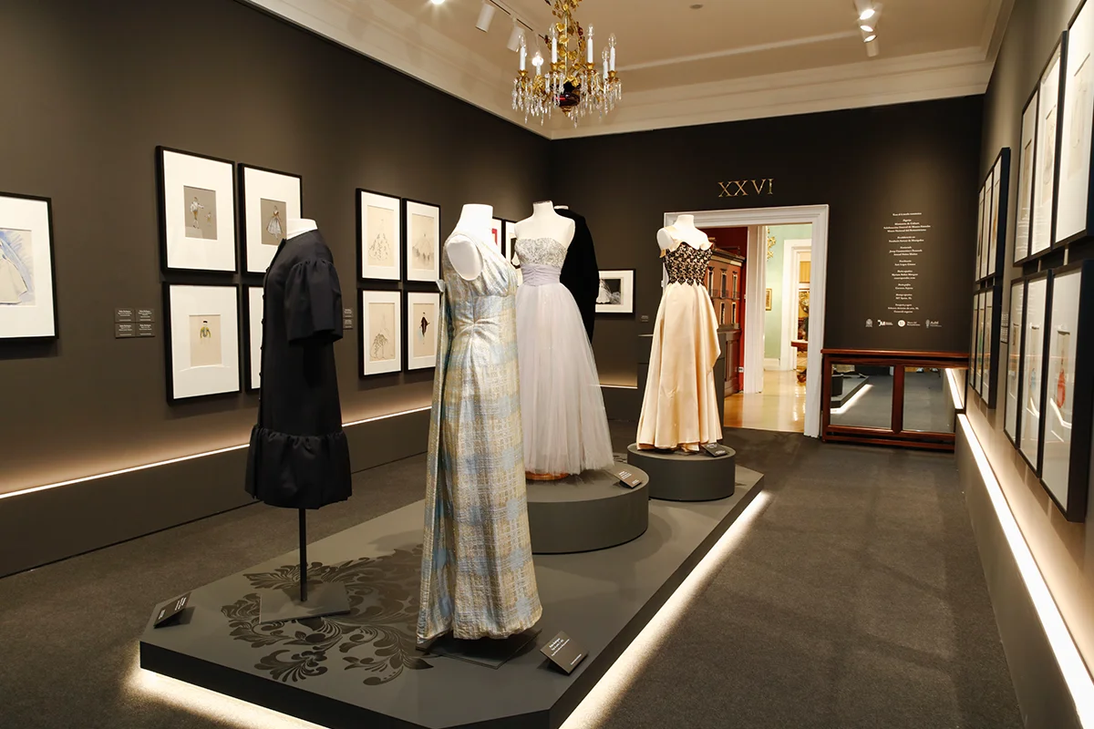 Museo Nacional del Romanticismo    La exposición Ecos de la moda romántica propone un sugerente diálogo entre la indumentaria del siglo XIX y la alta costura española de los siglos XX y XXI. La muestra reúne más de 40 trajes procedentes de la Fundació Antoni de Montpalau que conviven con las colecciones del museo en las estancias del palacio del marqués de Matallana. Diseños de creadores como Cristóbal Balenciaga, Pedro Rodríguez, Manuel Pertegaz, Elio Berhanyer, Sybilla, Jesús del Pozo, Teresa Helbig o David Delfín reinterpretan siluetas románticas como crinolinas, miriñaques o estampados florales. El recorrido culmina con una sala dedicada al modista Pedro Rodríguez, donde se exhiben trajes y figurines que evidencian su fascinación por las siluetas decimonónicas.