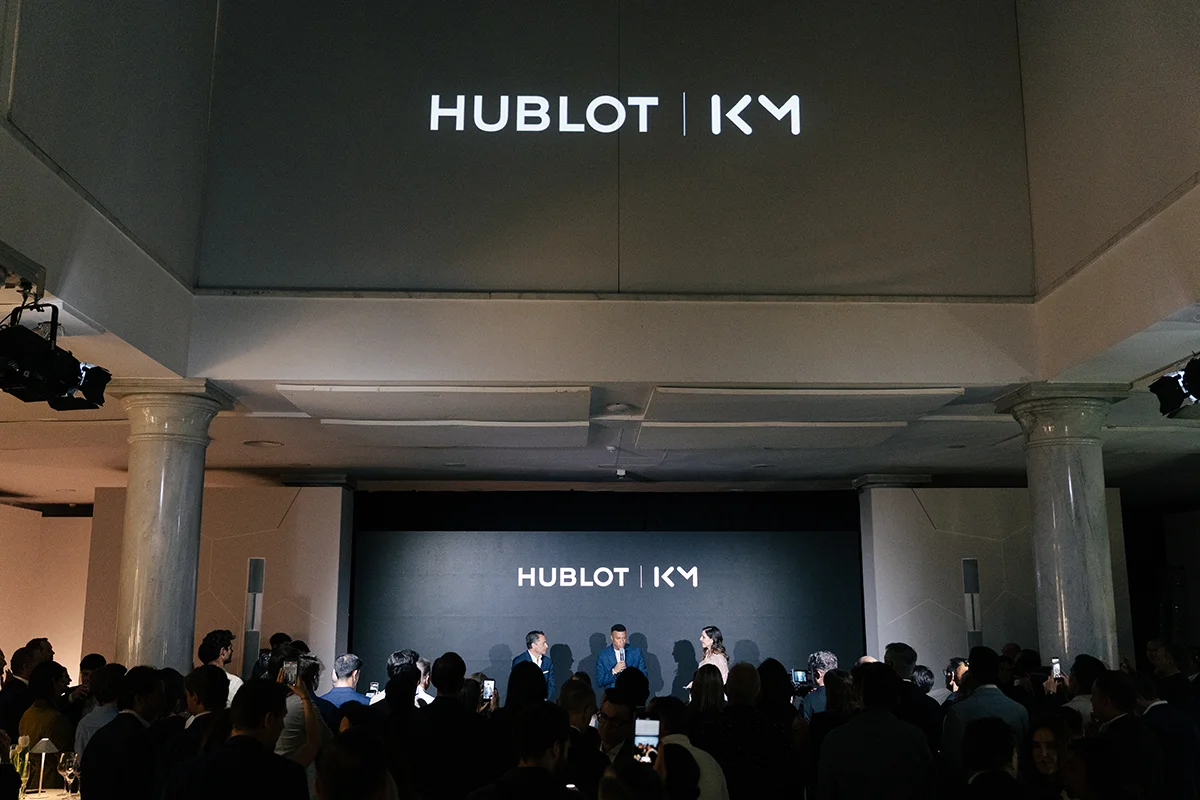La alta relojería y el deporte de élite volvieron a encontrarse en Madrid de la mano de Hublot y Kylian Mbappé. La presentación del nuevo Big Bang Reloaded Kylian Mbappé mostraba en público una edición limitada que convierte la personalidad y ambición del futbolista en una auténtica pieza de colección limitada a solo 200 unidades. La pieza destaca por su poderosa estética contemporánea y por reflejar el ADN innovador de la manufactura suiza. Fabricado en cerámica blanca pulida y oro King Gold de 18 quilates, el modelo incorpora detalles profundamente ligados al jugador, entre ellos el grabado “Trust Yourself” en el bisel o el número 10 en tono dorado, guiño directo a su icónica camiseta y a la filosofía que ha marcado su trayectoria profesional. Más allá de su diseño, el Big Bang Reloaded Kylian Mbappé también representa la excelencia técnica de la firma. En su interior alberga el calibre UNICO, uno de los cronógrafos integrados más avanzados de la firma suiza, capaz de combinar innovación mecánica y precisión de alta relojería con una estética deportiva y sofisticada. La presentación tuvo lugar en un exclusivo evento celebrado en el centro de Madrid, reunión de figuras del deporte, la moda y el entretenimiento como la estrella de la selección francesa, Iker Casillas o Paula Echevarría, entre otros, disfrutando de música en directo, una cuidada puesta en escena y una atmósfera contemporánea que celebraba la llegada de todo un icono.