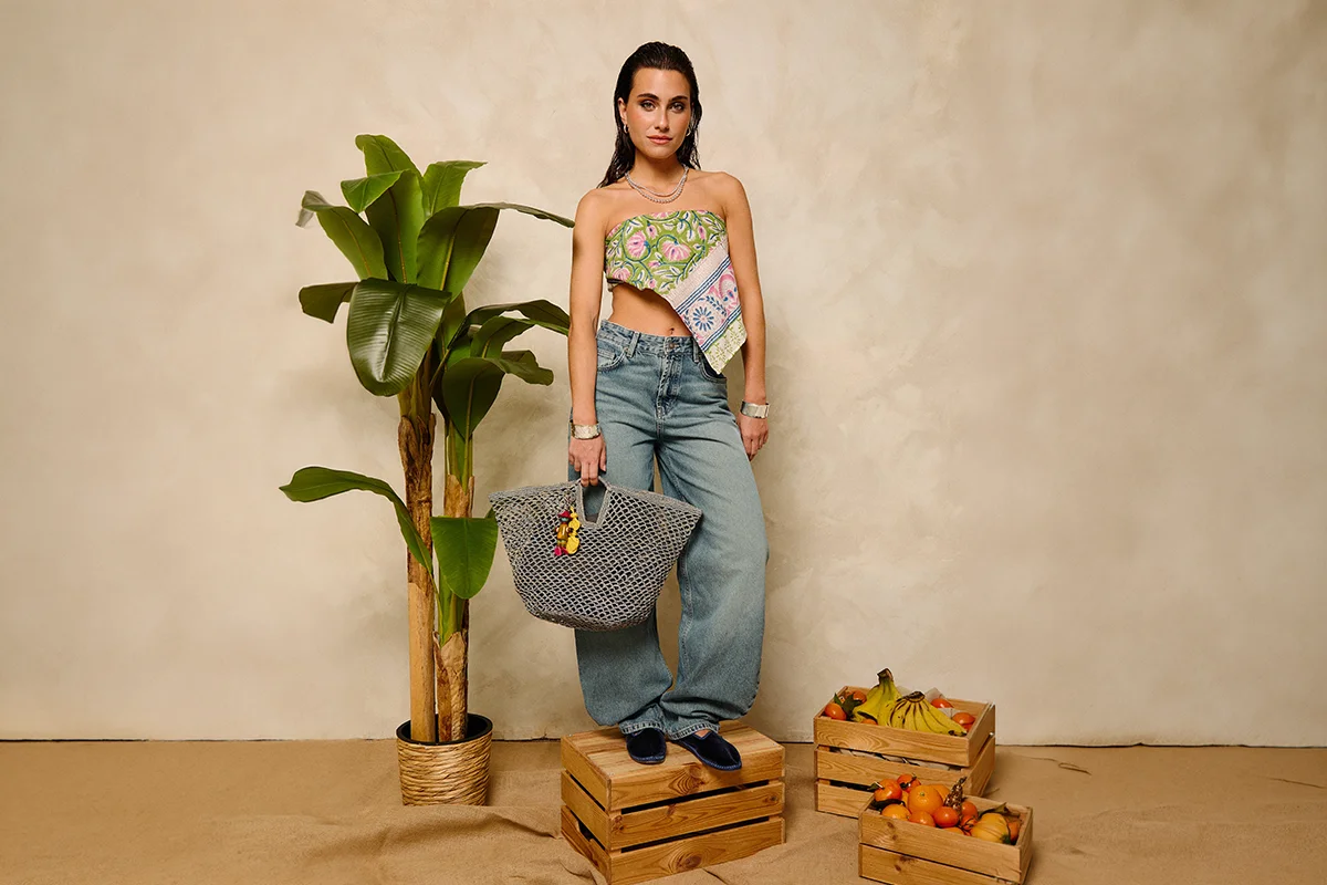 Hay marcas que no solo completan un look: lo transforman. Firmas capaces de convertir unos vaqueros básicos y una camiseta blanca en un estilismo con intención, personalidad y cierto aire aspiracional. Nombres como Pescuezo, Les Georgettes, Parfois o Foránea han encontrado precisamente ese espacio: el de las marcas que elevan cualquier outfit a través de los detalles. Porque al final, la verdadera personalidad no está en vestir de arriba abajo una marca, sino en encontrar esas piezas capaces de hacer que lo sencillo parezca pensado y personal. Los accesorios se han convertido en el lenguaje definitivo del estilo. Un collar potente, un bolso especial o una pieza artesanal bien elegida redefinen por completo la estética de quien los lleva. El auge de las firmas independientes y accesibles con fuerte identidad estética ha democratizado esa sensación de sofisticación. El secreto está en saber mezclar. Ahí es donde destacan marcas como Parfois. La firma portuguesa ha conseguido posicionarse como una referencia de accesorios de tendencia gracias a su capacidad para reinterpretar códigos minimalistas a precios asequibles. Bolsos estructurados, joyería que adorna el cuello, chaquetas y accesorios para el cabello forman parte de ese universo effortless que tanto triunfa en redes y street style. parfois.com La joyería está redefiniendo los looks. Ya no se trata únicamente de adornar, sino de aportar identidad, y Les Georgettes es uno de los ejemplos más interesantes. La firma francesa popularizó un concepto muy concreto: joyas personalizables con bandas intercambiables de cuero y vinilo. El resultado son piezas versátiles que cambian según el estado de ánimo o el look del día. Ese tipo de diseño conecta perfectamente con la moda actual, donde las consumidoras buscan piezas funcionales pero especiales. Una pulsera oversize o un brazalete arquitectónico pueden transformar instantáneamente un estilismo neutro en uno mucho más sofisticado. Además, el auge de los charms, chokers y la joyería maximalista confirma que los accesorios viven uno de sus momentos más fuertes en la industria. lesgeorgettes.com Uno de los fenómenos más interesantes de la moda reciente es el crecimiento de firmas nicho con una identidad muy marcada. En lugar de seguir tendencias masivas, estas marcas construyen su propia comunidad. Pescuezo entra dentro de esa categoría de firmas que funcionan casi como objeto de culto digital: piezas llamativas, mezcla de color, artesanía y un punto editorial que convierten cualquier look sencillo en algo mucho más interesante. Sus nuevas capas ligeras están pensadas para sobreponer y aportar un toque de estilo a los looks. Estampados Liberty, rayas —muchas rayas—, toques en amarillo limón, azules y rosas, junto a un divertido estampado de perritos, flores y los ya característicos tonos naturales, conviven en una propuesta que equilibra tradición y frescura para que los cuellos sean los protagonistas, incluso en verano. pescuezos.es Lo mismo ocurre con Foránea, cuyo atractivo reside precisamente en esa sensación de exclusividad relajada: accesorios con carácter, inspiración artesanal y estética contemporánea que encajan perfectamente con la tendencia actual hacia lo auténtico y lo imperfecto. Una nueva marca que invita a descubrir el mundo a través de la artesanía, poniendo en valor las historias, las manos y las culturas que hay detrás de cada pieza. Su universo se construye a partir de una cuidada selección de accesorios hechos a mano en distintos lugares del mundo: desde bolsos y cestas de rafia de Madagascar hasta crochet bordado en Ecuador, joyas de tagua, piezas de Turquía o textiles de la India. Cada pieza es el resultado de un proceso manual, donde el tiempo y la dedicación forman parte de su valor, apostando por una forma de consumo más consciente y especial. foranea.com