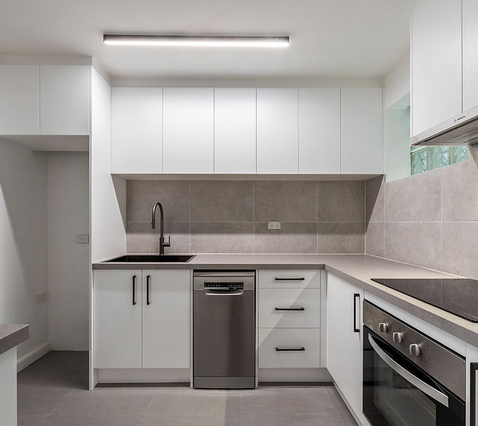 Kitchen renovation in Elsternwick featuring white cabinetry, grey benchtops, black handles and a modern minimalist layout
