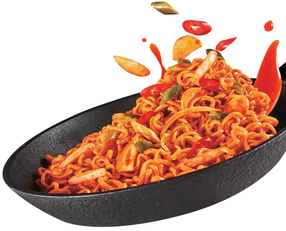 A black skillet of spicy stir-fried ramen noodles with chili peppers, garlic, and scallion