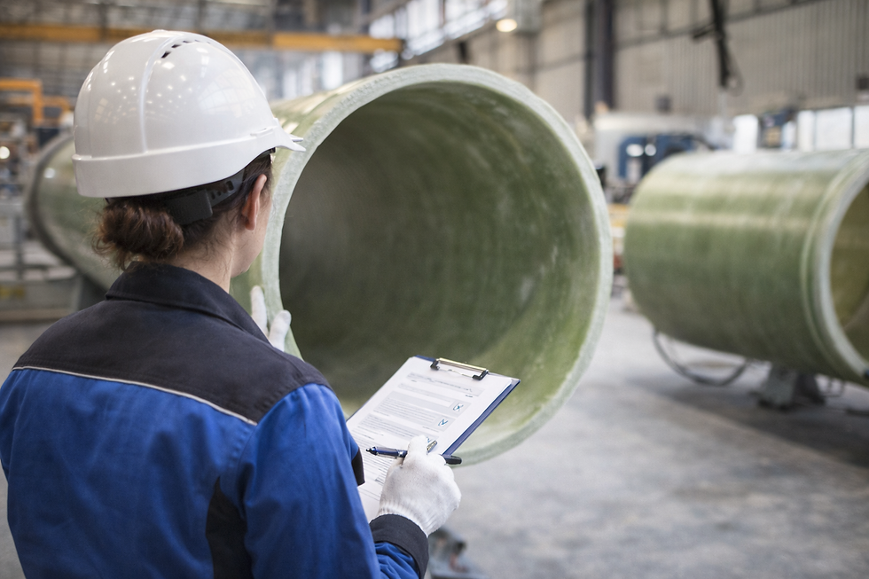 Female occupational safety specialist inspecting a GRP pipe in an industrial production facility.