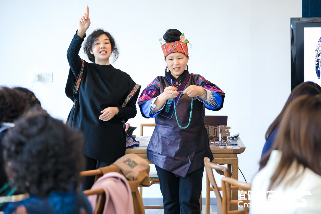 Sharing the stage with a Miao woman demonstrating her work