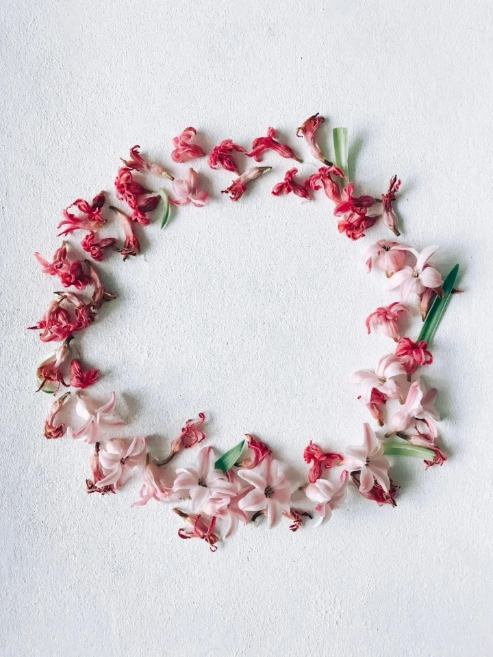 A minimalist floral wreath with small pink and red flowers with green leaves. Great for those seeking inspiration to make a wreath for front door decorations.