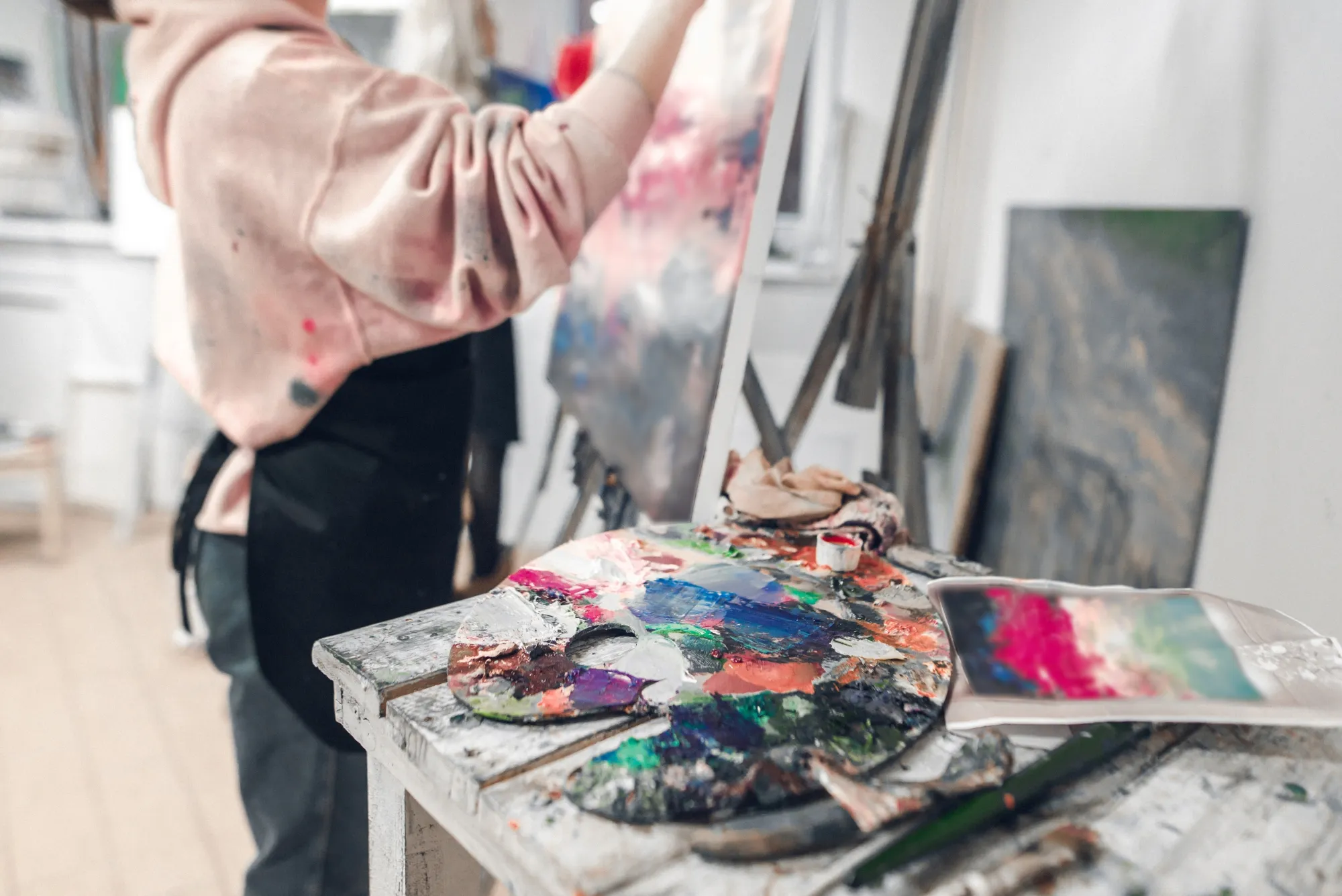 Artist commissioned to make customer artwork for unique gift idea, standing at painting palette with many colors of paints to create a unique art on canvas for a special someone and new house gift experience of something unique never tried before