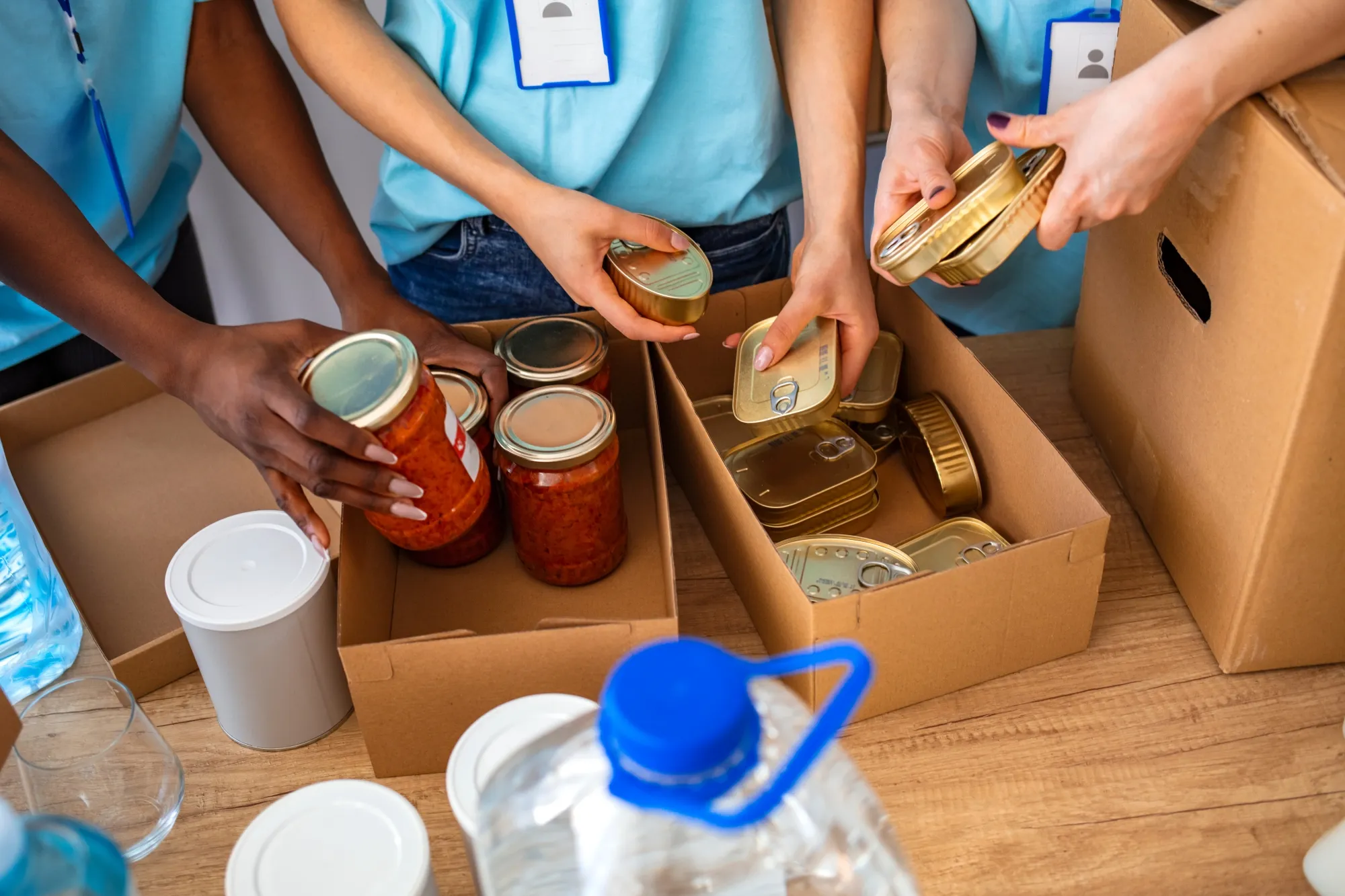 Sorting of different jars and cans by people in blue shorts as part of a donation drive to put goods in boxes after given to special someone as gifts for people who have everything so can contribute to helpful cause and humanitarian ethical aid worldwide help for improved mental health and connection