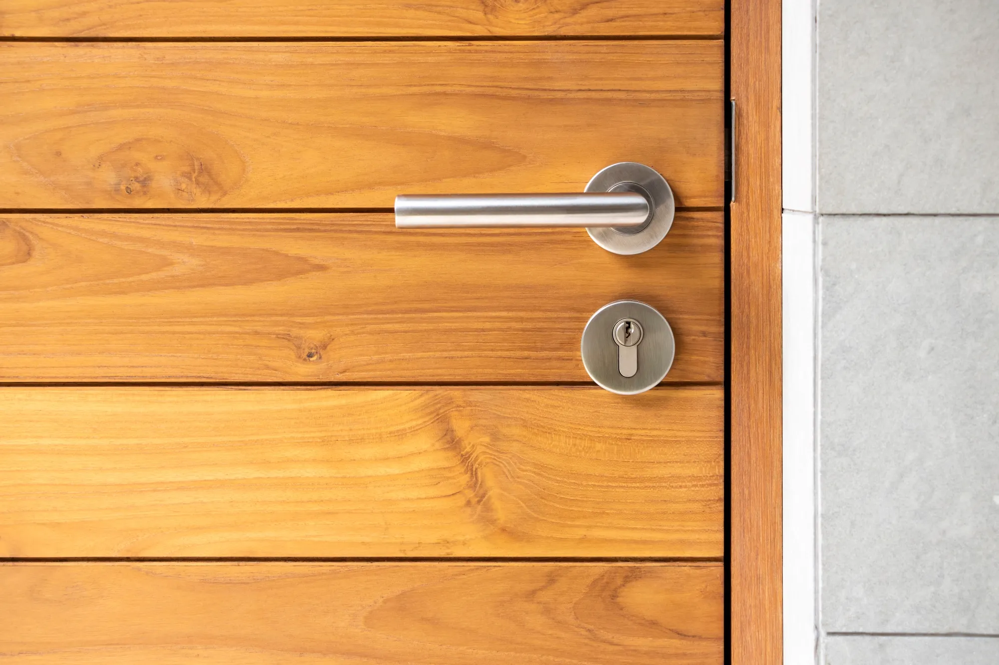 Modern stainless steel door handle and key lock on a sleek timber panel door for entryway decor year round and all seasons winter, summer, autumn or fall and spring for seasonal decorations