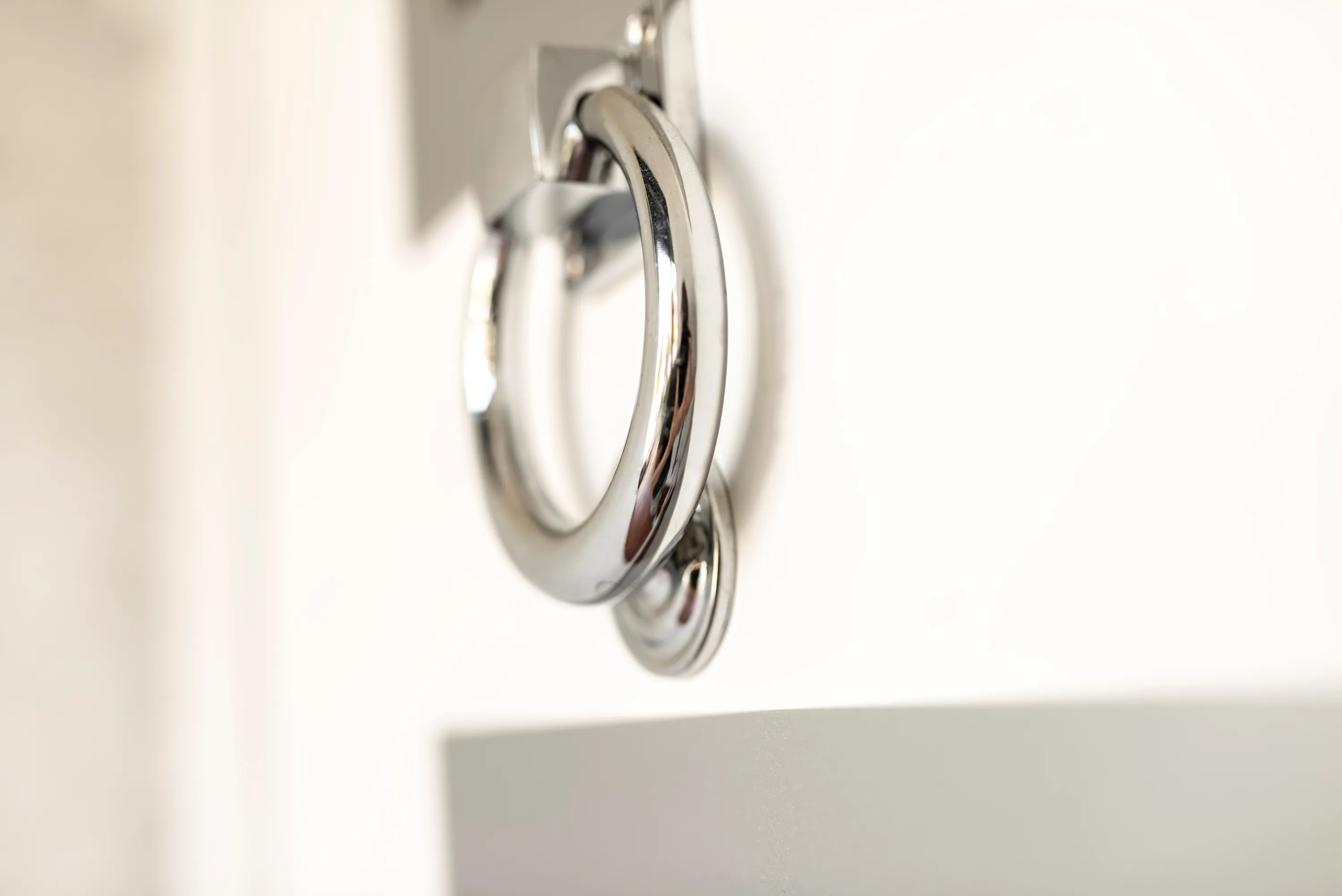 Silver door knocker for modern front door decor ideas on white simple door with metallic smooth handles and sleek design for people interested in home decor both modern, vintage, farmhouse or boho