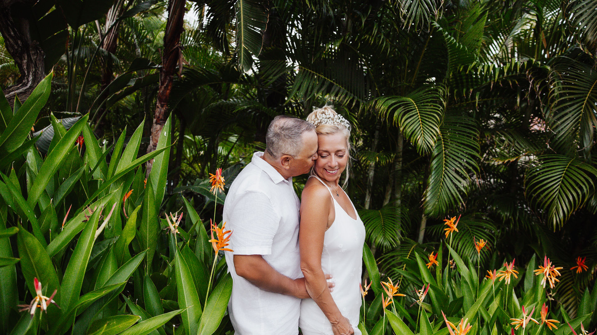 Couple photographed during their honeymoon, among tropical greenery in Aruba during a relaxed outdoor photography session