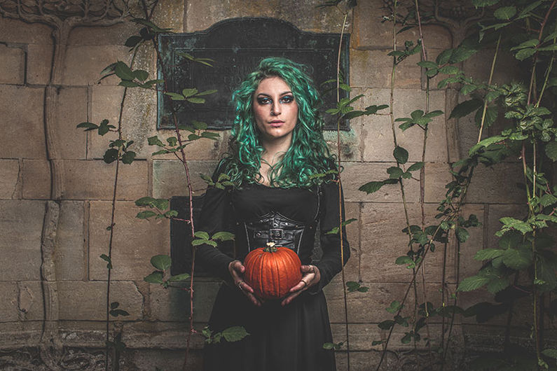 Halloween photo shoot, pretty girl with green hair holding a pumpkin