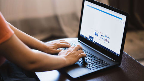 Close-up of person typing on a laptop indoors, showcasing technology use.