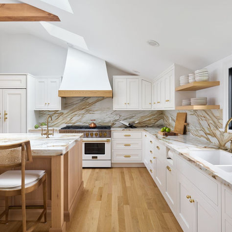 Spacious kitchen with white cabinets, marble countertops, and hardwood floors. Brass fixtures and large windows add elegance. Peaceful ambiance