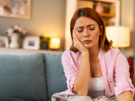 Woman sitting on couch in home feeling depressed, sad, lonely