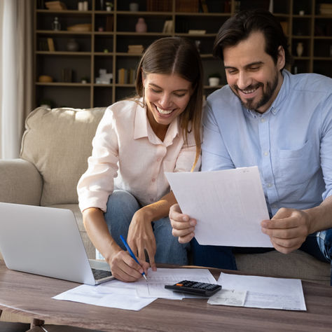 Happy couple looking at their expenses, filing their taxes