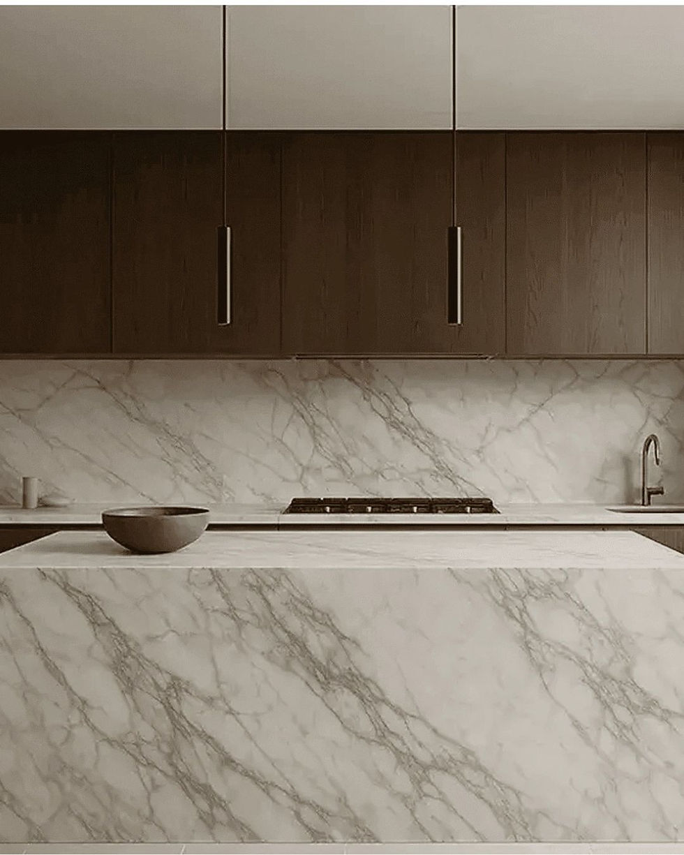 Modern kitchen with marble island, dark wood cabinets, a bowl on the counter, stove, and sink in a sleek minimalist space