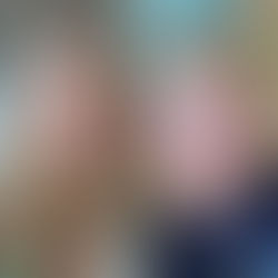 Two people smiling indoors. The child wears purple glasses and a shirt with partial text "BRING THAT." Stairs in the glass background.