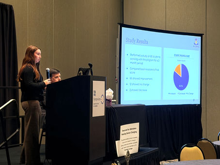 Woman presenting at conference with microphone, next to a screen showing study results and a pie chart. Audience chairs in foreground.