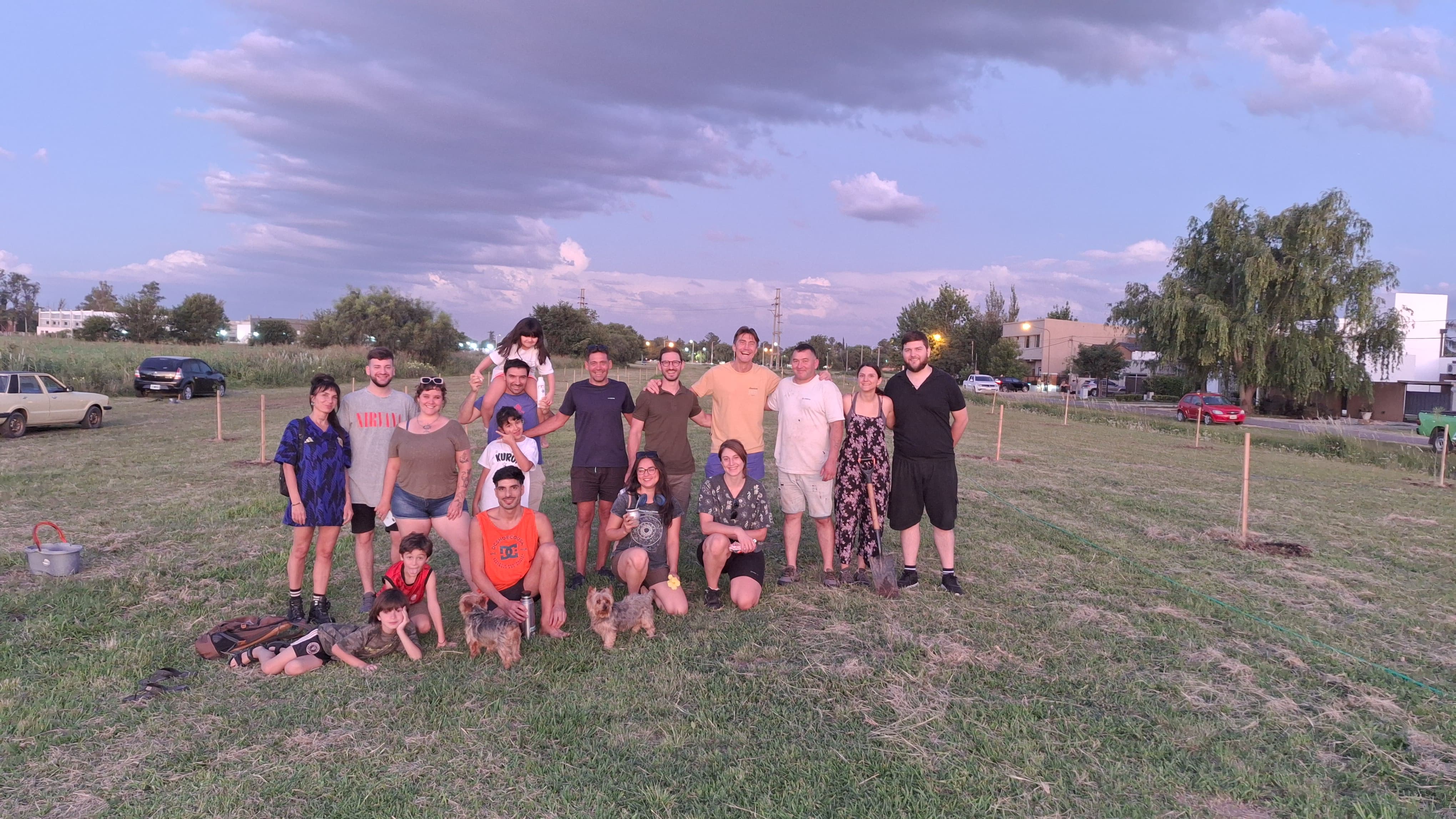 Participantes de una jornada de forestación junto a árboles jóvenes con tutores