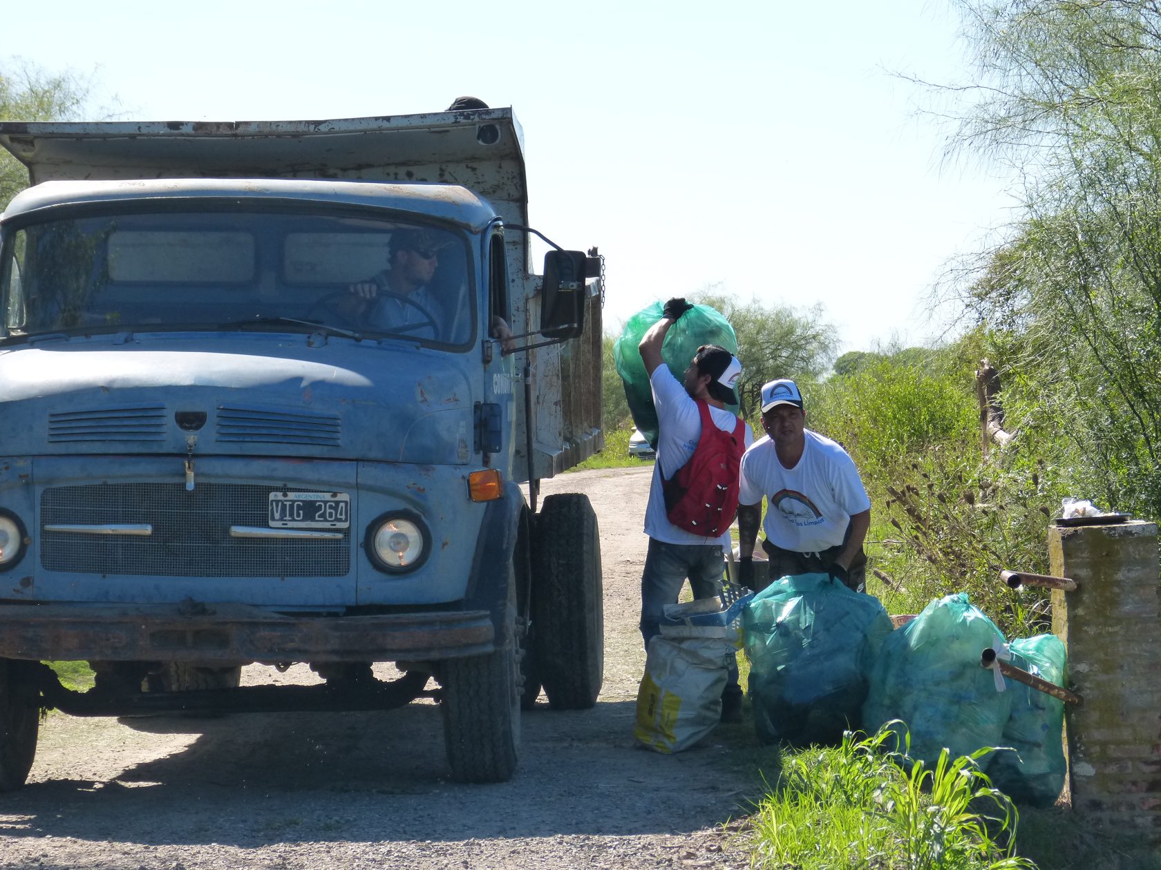 Integrantes de una jornada ambiental junto a un camión y bolsas con residuos retirados