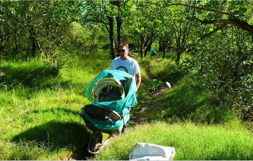 Voluntario trasladando materiales de recuperación ambiental por el sendero arbolado del sector Puente Cirilo