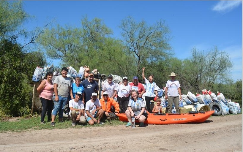 Grupo de vecinos y voluntarios junto a los residuos recolectados y un kayak en Puente Cirilo