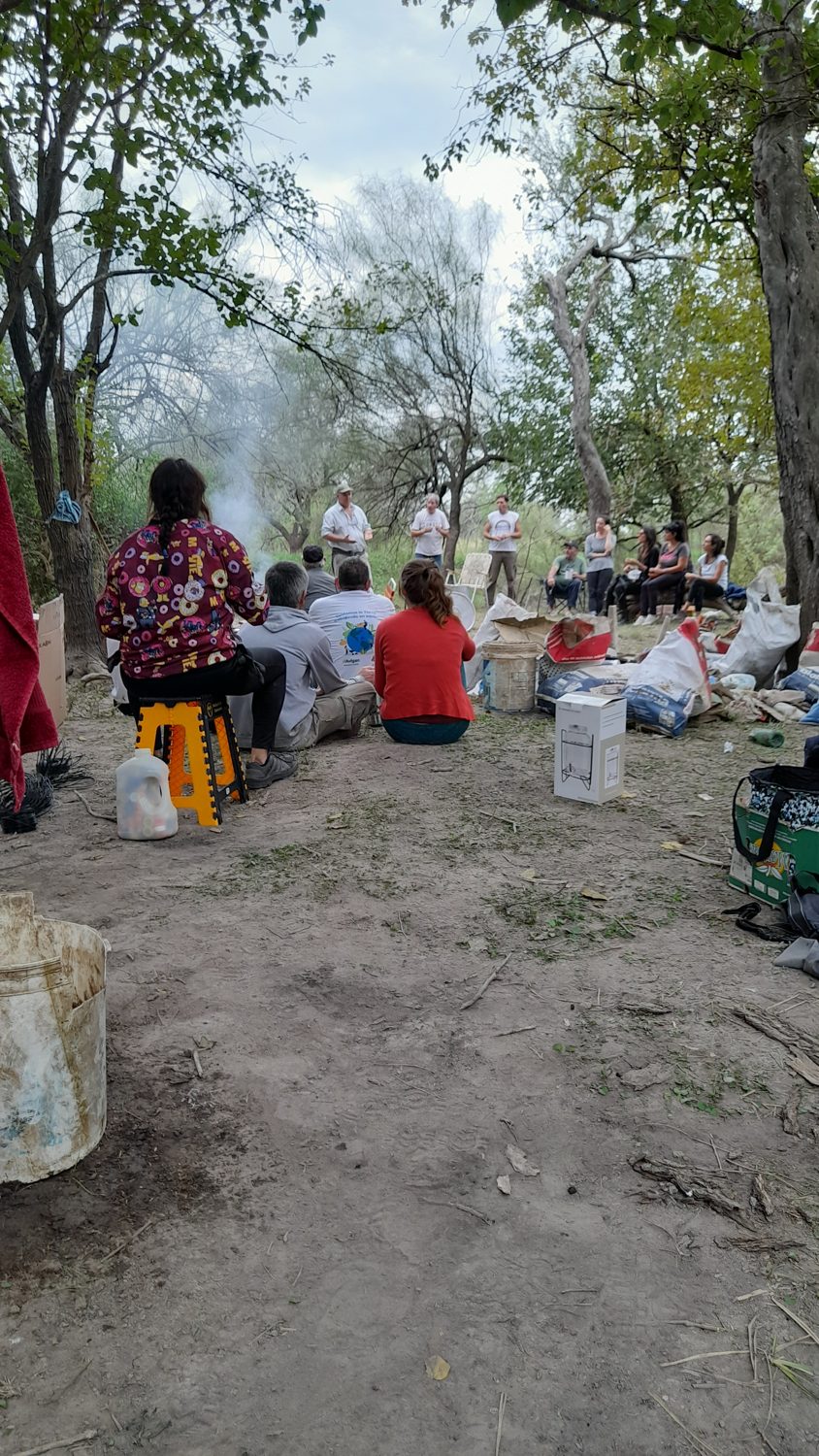 Grupo de voluntarios reunidos bajo los árboles luego de una actividad de recuperación ambiental