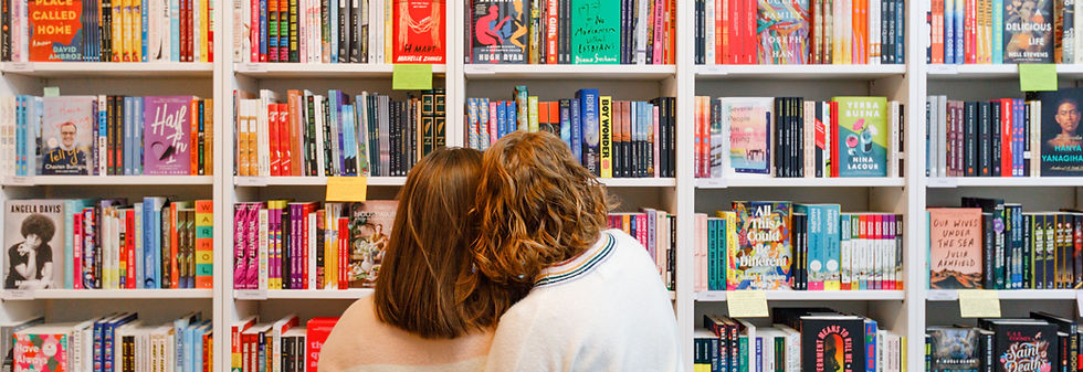 the back of a brunette and blonde head standing in front of a colorful book case
