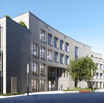 Großes, modernes, graues Gebäude mit vielen Fenstern, Menschen, die draußen stehen, Bäume und Bänke auf dem Bürgersteig, klarer blauer Himmel, graue Kopfsteinpflasterstraße, weißer Bürgersteig und Grün auf dem Dach, mit einem eleganten und zeitgenössischen Architekturstil.