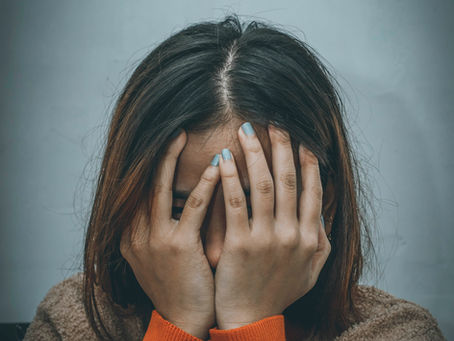 Frau mit langen Haaren vergräbt ihre Hände ins Gesicht